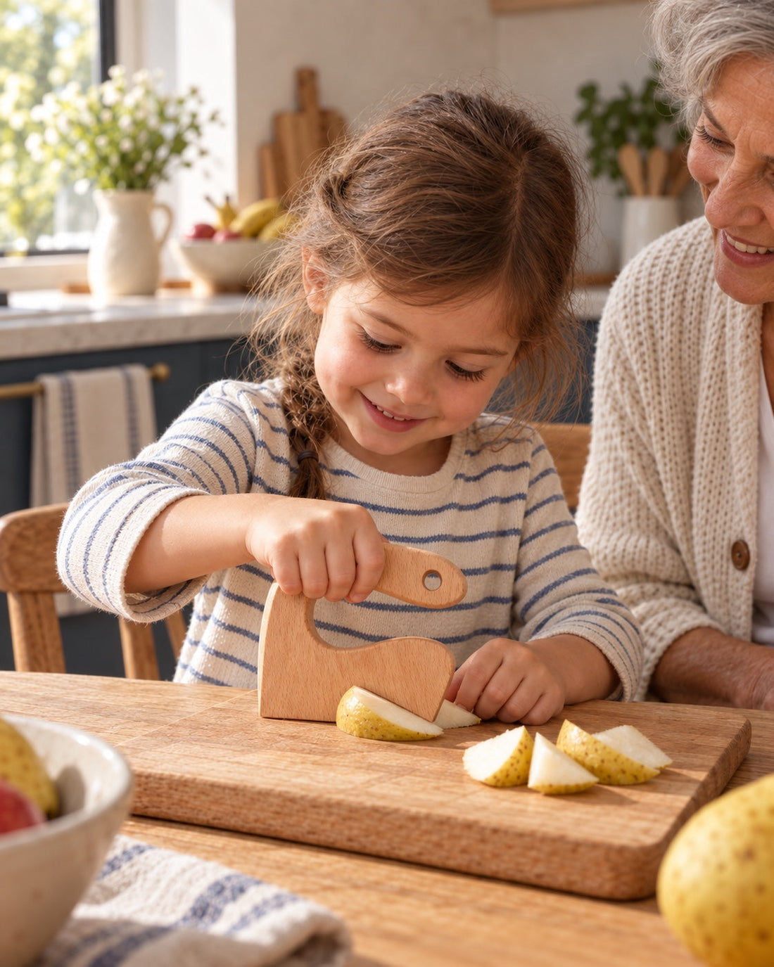 Une enfant découpe une poire mûre avec mamie.