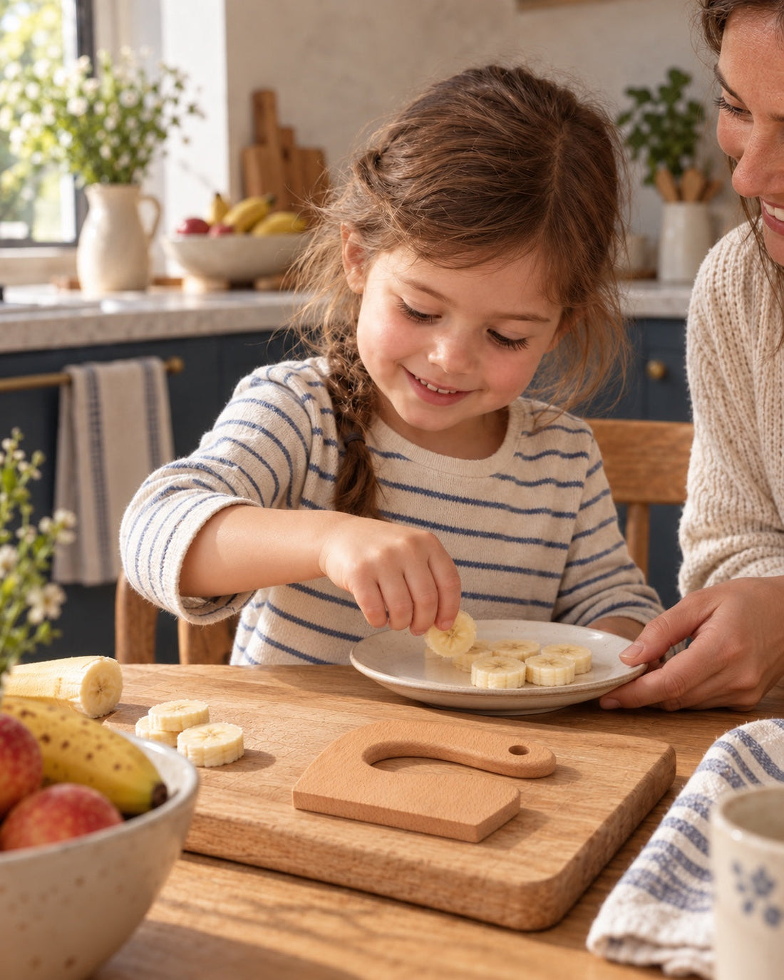 Une enfant termine son assiette de fruits, le couteau en bois à portée.