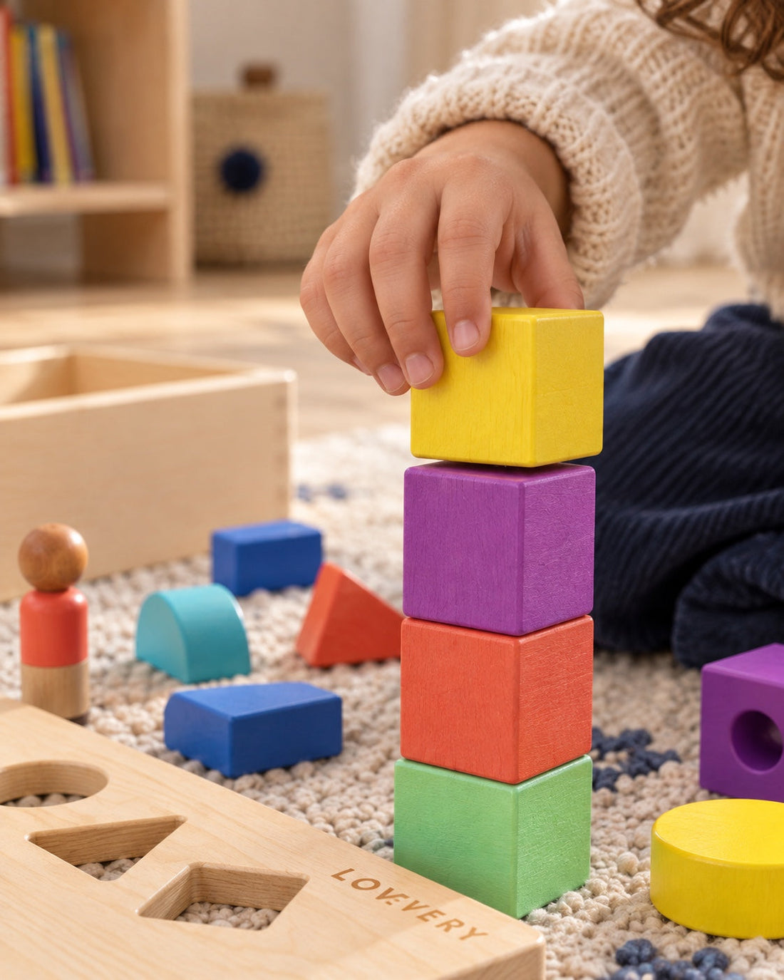 Une petite main pose un cube sur une construction.